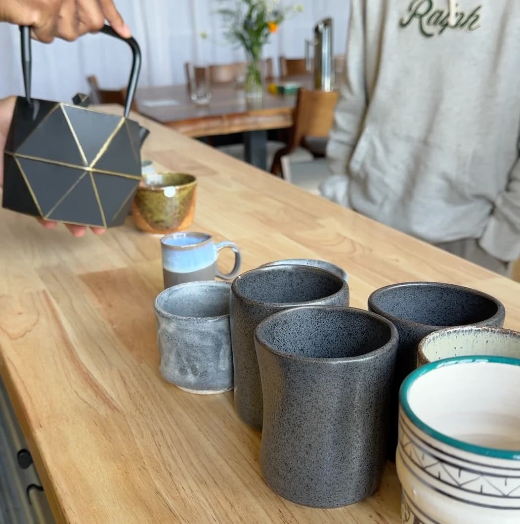Tea is poured into a collection of ceramic cups before the shared activity.